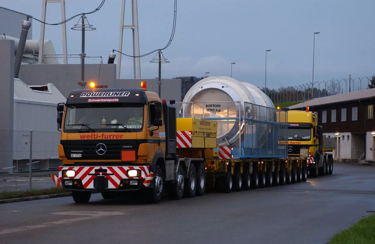 Ein Schwerlasttransport transportiert einen Castor-Behälter, in dem sich radioaktive Abfälle befinden. Die Zugmaschine hat 4 Achsen. Der Tieflader-Anhänger hat 12 Achsen.